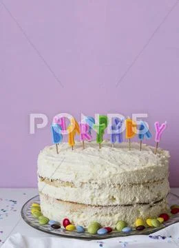 A Child's Birthday Cake Decorated With Colourful Letter Candles