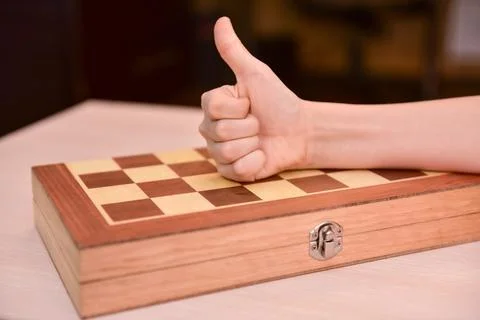 Child's hand on the chessboard showing thumb up. cool game at home Stock Photos