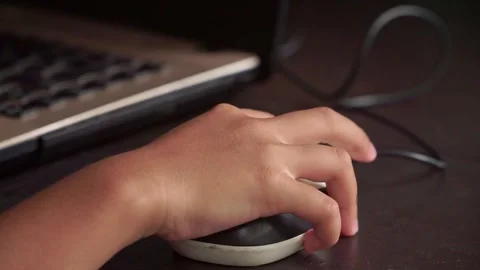 Child’s hand on a computer mouse with blurred monitor, concept of online Stock Footage 324959837