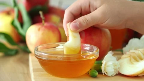 A child's hand dips an apple slice into honey. Rosh Hashanah. A family festive m Video stock 312377021