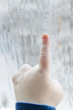 The child's hand draws patterns on the frozen window in winter Stock Photos