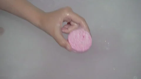A child's hand drops a pink bath bomb into the bath Video stock 340770832