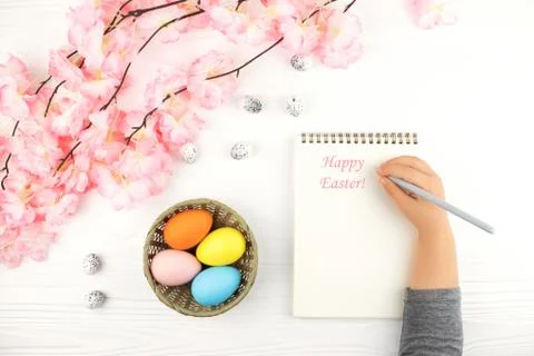 Child's hand with empty notebook on Easter background. Stock Photos