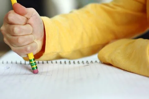 Child's hand erasing with pencil on notebook paper Stock Photos