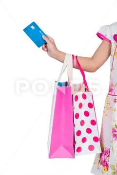Child's hand holding credit card and colorful shopping bags Stock Photos