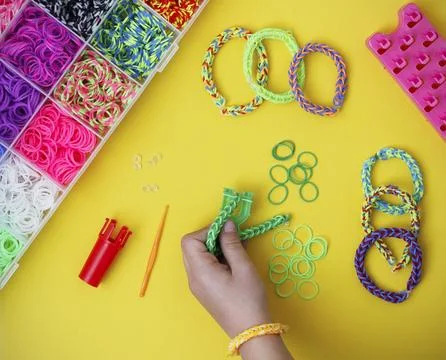 Child's hand holding a work in progress loom bracelet on yellow background Stock Photos