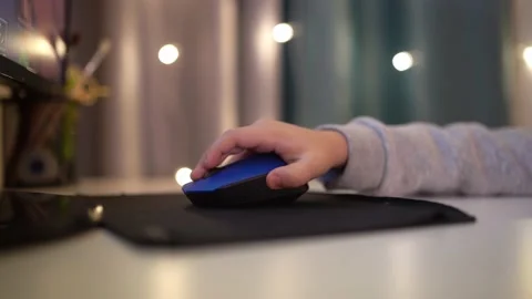 A child's hand holds a computer mouse and plays a computer game Stock Footage 176512395
