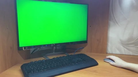 Child's hand moves mouse next to computer with green chroma key screen. Stock Footage 221444572