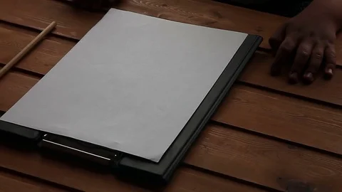 The child's hand next to a blank sheet of paper and a pencil on the table Stock-Footage 75558998