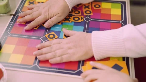 Child's hand placing tile with X onto colorful board during game tic tac to.. Stock Footage 335085717