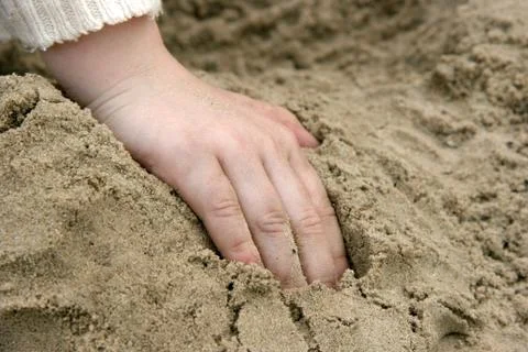 Childs hand in sand Stock Photos