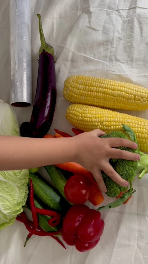 Child’s Hand Selecting Fresh Broccoli among Colorful Vegetables – Top View Stock Footage 317448073