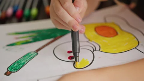 The child's hand on the table draws a duck with a color marker in a coloring Stock Footage 220538001