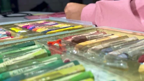 Child's hand take a crayon from the box, colorful art supplies visible, Stock Footage 343424187
