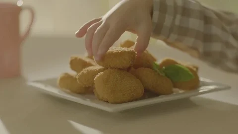 The child's hand takes an appetizing nuggets from the plate. Stock Footage 83723157