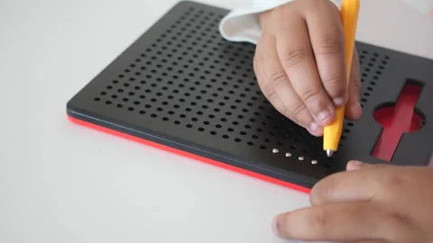 Childs hand using magnetic drawing board to write letters on white surface .. Stockbeeldmateriaal 331836005