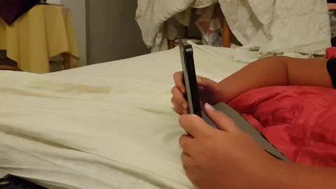 The child's hands are holding the tablet. a child is playing video games on the Stock Footage 221335952