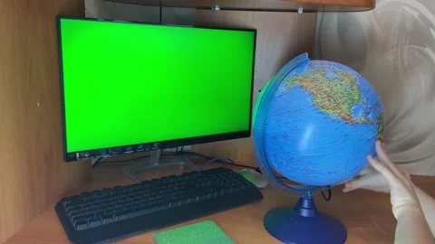 The child's hands are spinning the globe next to the computer Stock Footage 221444584