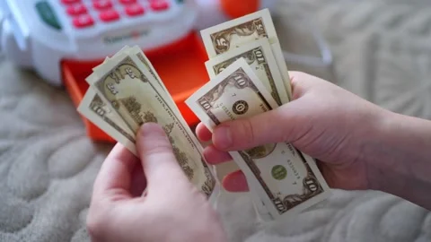 A child's hands carefully handle play money, the crisp bills fluttering like Vidéo 302916904