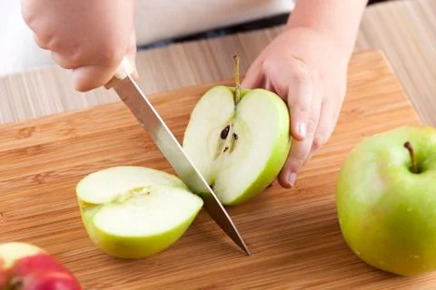 Child's hands cutting apple Stock Photos