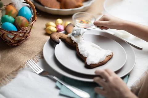 Childs hands decorating Easter bunny shaped cookie with icing on festive Stock Photos