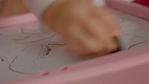 Child's hands drawing and erasing on a blackboard, creative play in action Stock Footage 329227323