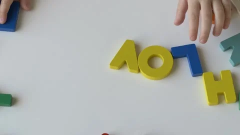 Childs hands engaged in playful learning, arranging colorful alphabet letters on Video stock 318293908
