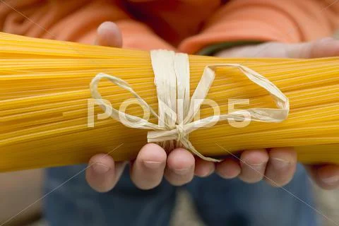 Child's hands holding a bundle of spaghetti Stock Photos