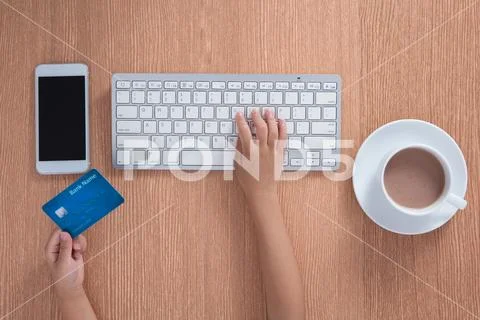 Child's hands holding credit card and typing on keyboard Stock Photos
