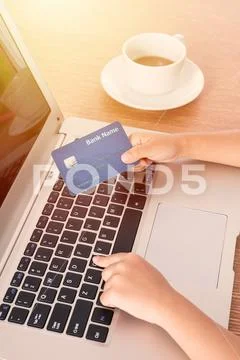 Child's hands holding credit card and typing on keyboard Stock Photos