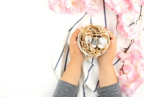 Child's hands holding Easter eggs on wooden background. Stock Photos