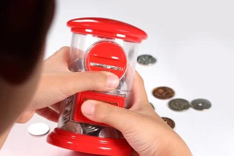 Child's hands holding a postbox-shaped piggy bank Stock Photos