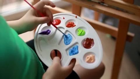 A child's hands picking up paint from a palette with a brush Stock Footage 300981252