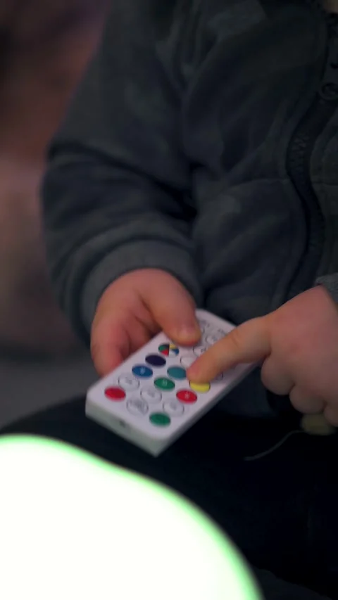 Child's Hands Playing with Remote Control: Vertical Close-Up Stock Footage 325056547