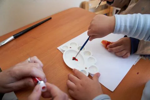 Child's hands pulling paint from palette. Preschool and family Stock Photos