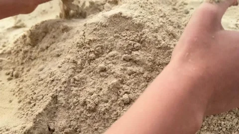 A childs hands scooping sand on the beach, building a sandcastle in a playful Video stock 303359371