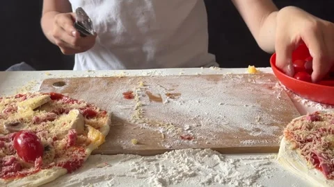 Child's hands slicing cherry tomato on wooden board, homemade cooking and pizza Stock Footage 337414546