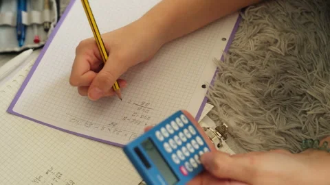 Child's hands writing down math equation on grid paper with pencil while si.. Stock Footage 318367450