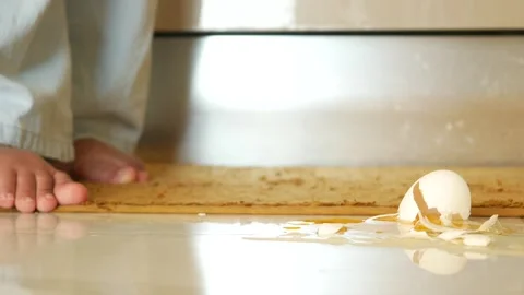 A childs tiny footsteps are seen next to a broken egg lying on the kitchen floor Video stock 296859260