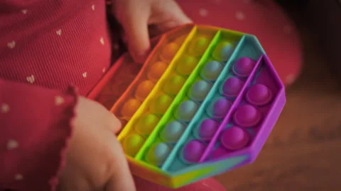 Childs tiny hands clutch bright multi-colored anti-stress toy pressing the s Stock Footage 334546234