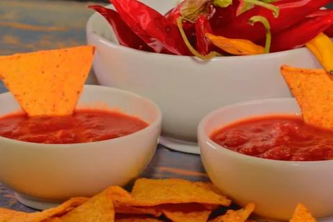 Chili corn-chips with salsa dip and chili peppers on wooden background Stock-Fotos