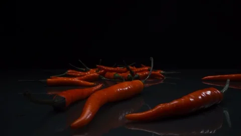 Chili pepper falls on a black table on a dark background. Close-up. Video stock 125476377