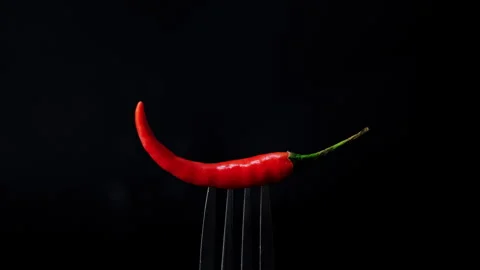 Chili pepper on fork with flames on black background. Burning red chili Video stock 260532939