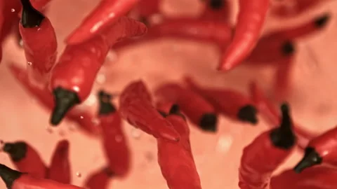 Chili peppers fly up and fall down on a light background. Filmed on a high-speed Stock Footage 322751010