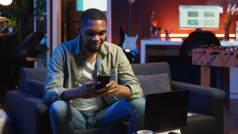 Chill self employed guy enjoying a break with his mobile phone on sofa Vídeos de archivo 308335702