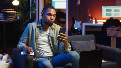 Chill self employed guy enjoying a video call on mobile phone at home Stock Footage 308336153