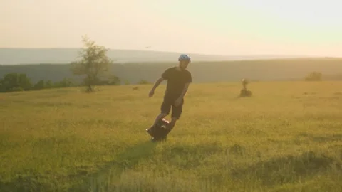 Chilled-Out Guy Glides on an Electric Unicycle in Sunny Rural Summer Scene Stock Footage 312109481