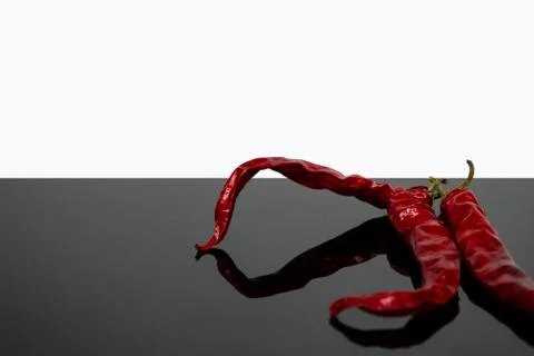 Chilli peppers on a reflective surface Stock Photos