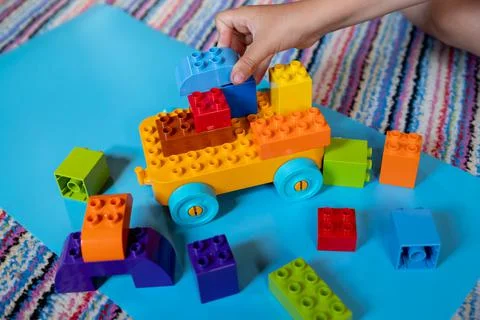 Chils playing with construction toy blocks building a tower in a sunny Stock Photos