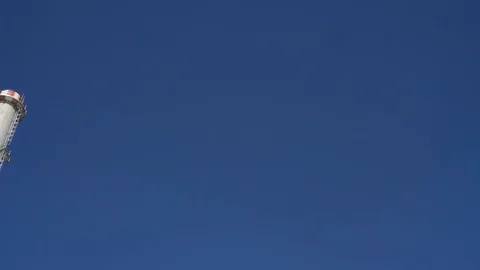 Chimney and facade of garbage recycling plant against blue sky and green palms 動画素材 118930452